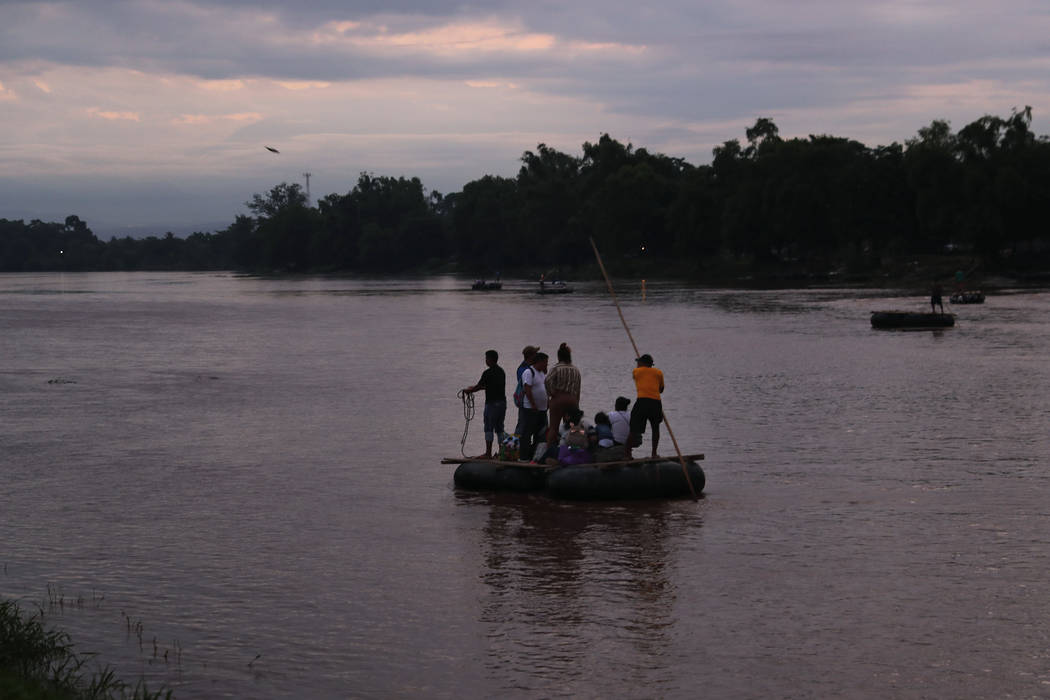 Migrants travel from Guatemala to Mexico on a raft, pushed with a pole by its operator who char ...