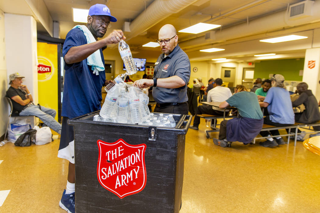 Client/volunteer Lionell Broughton assists homeless services coordinator Ryan McDonald in passi ...