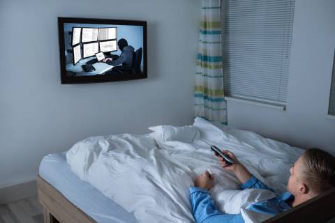 A man watches television in bed. (Getty Images)