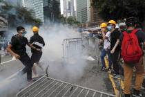 Protesters react to tear gas during a large protest near the Legislative Council in Hong Kong, ...