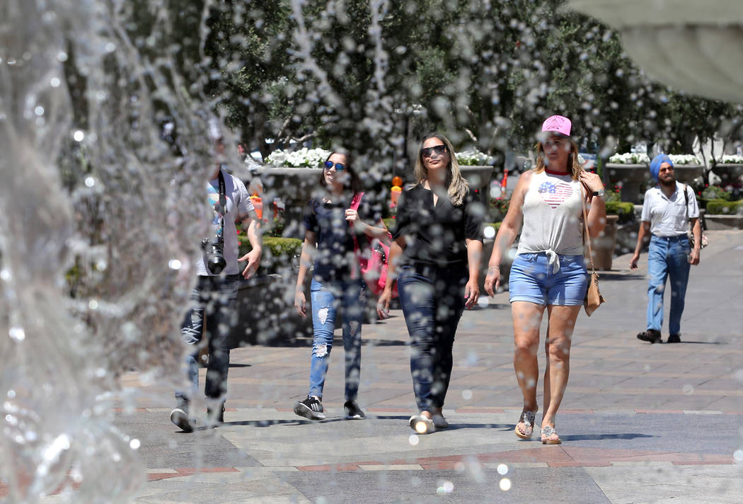 Tourists, who declined to give their names, walk past The Venetian water fountain on a hot day ...