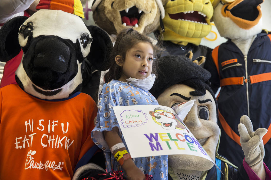 Zaryah Robbs, second from left, 8, takes a photo with the Chick-fil-A Cow, left, and the LV Lig ...