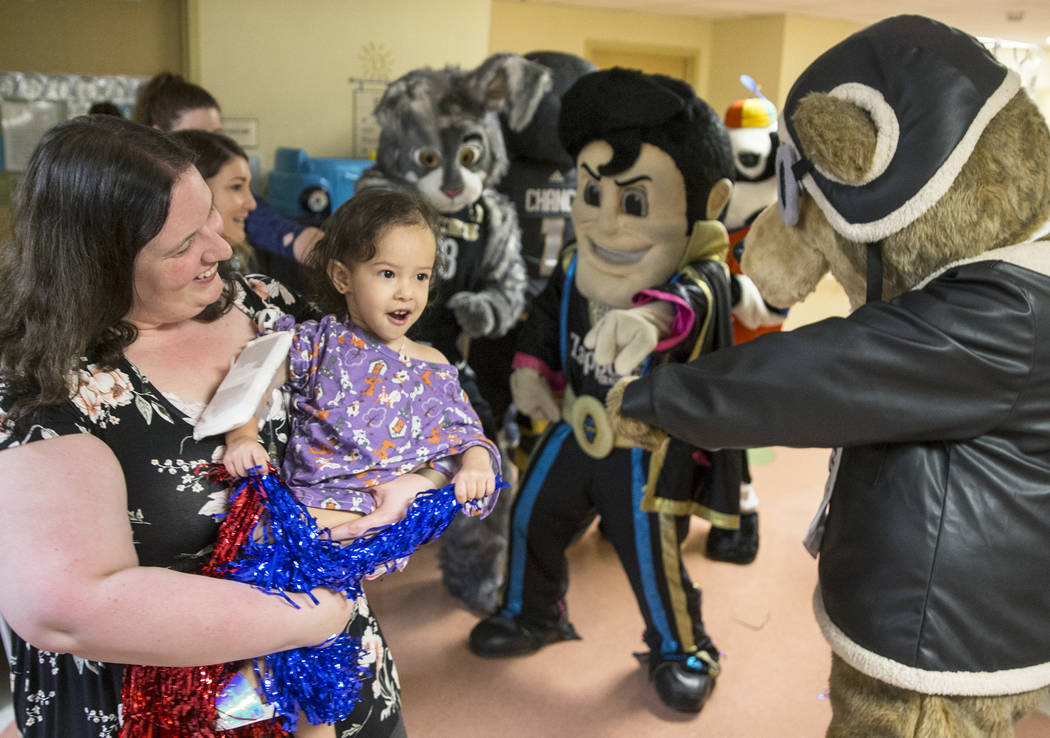 Krystle Hunter, left, holds Camila Silva, 2, as they dance with a group of Las Vegas-based masc ...