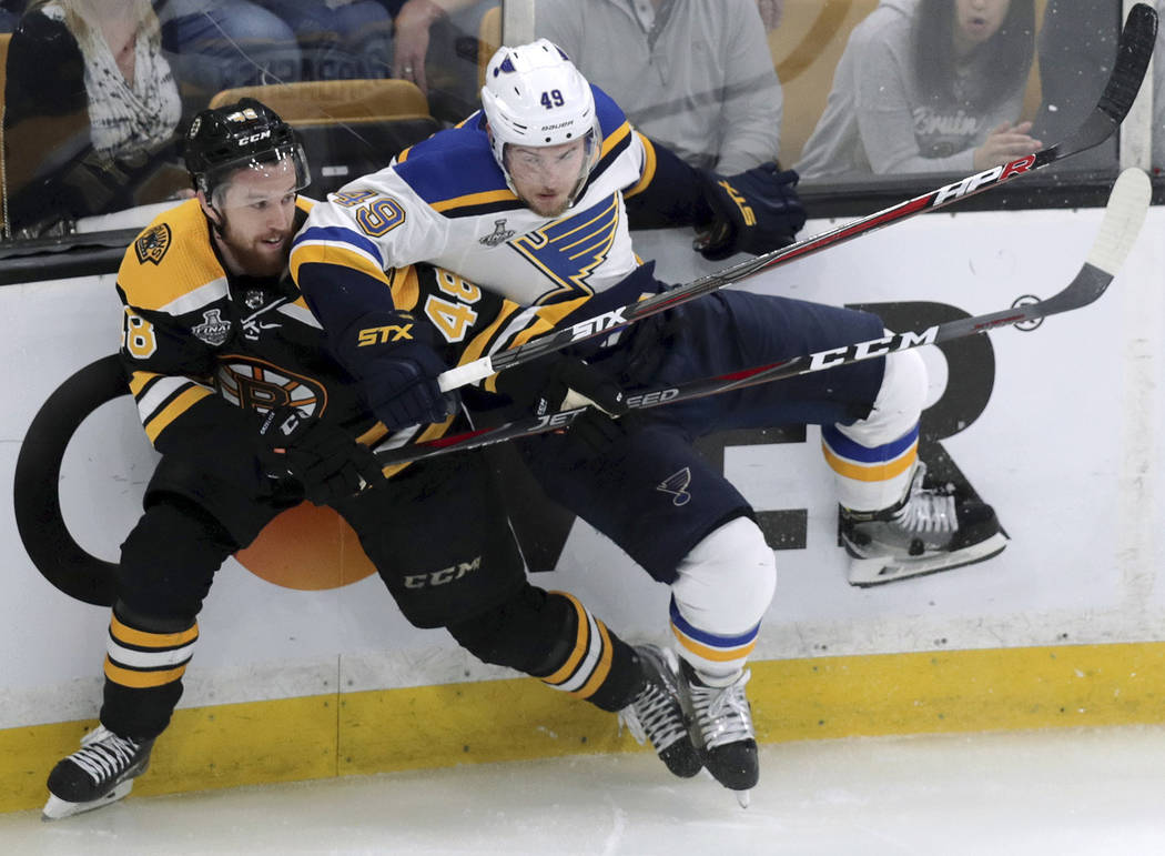 Boston Bruins' Matt Grzelcyk, left, and St. Louis Blues' Ivan Barbashev, of Russia, crash into ...
