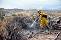 A firefighter hoses down the area on Mount Rose Highway and Edmonton Drive in Reno, Oct. 14, 20 ...