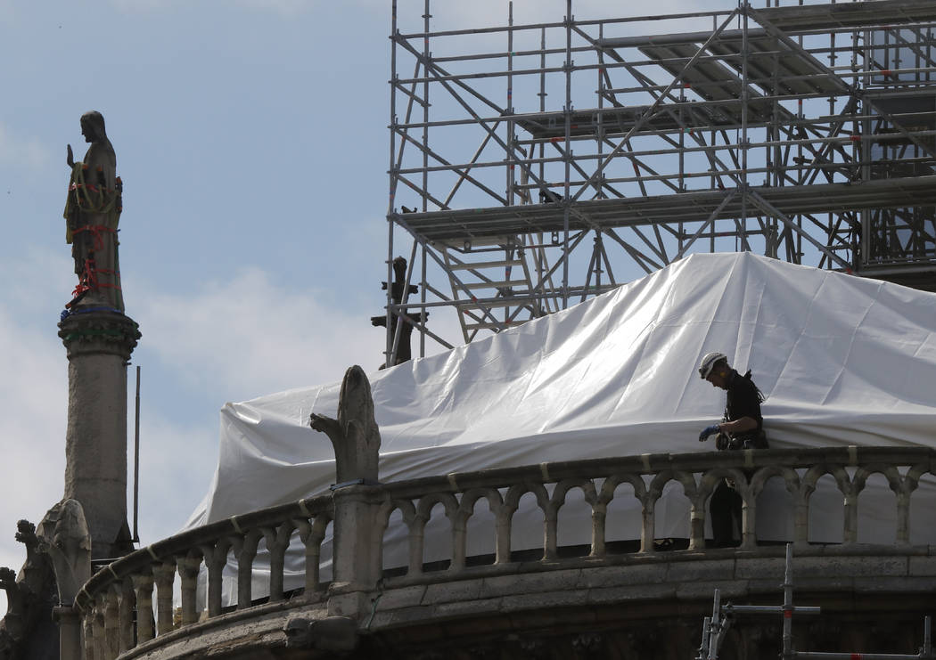 FILE - In this April 26, 2019 file photo, a worker checks the waterproof tarps on Notre Dame ca ...
