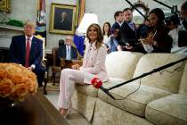 President Donald Trump looks on as first lady Melania Trump talks with reporters during a meeti ...