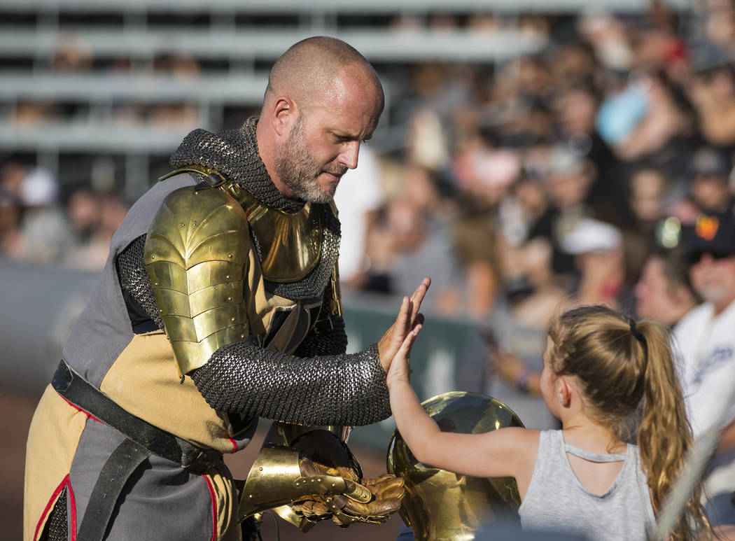 Lee Orchard, aka The Golden Knight, left, high fives a fan during the Battle For Vegas Charity ...