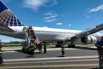 This photo provided by Caroline Craddock shows emergency personnel help passengers off a plane ...