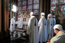 The Archbishop of Paris Michel Aupetit, second left, leads the first mass in a side chapel, two ...