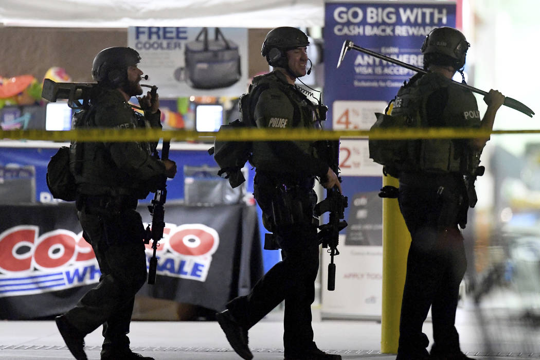 Heavily armed police officers exit the Costco following a shooting inside the wholesale warehou ...