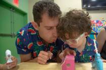 Michael Sherman of Las Vegas, left, blows hot glue to cool off with his son Bernard, 4, during ...