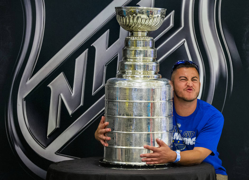 St. Louis Blues fan Chad Sparks from Troy, Ill., poses with the Stanley Cup, the most recogniza ...
