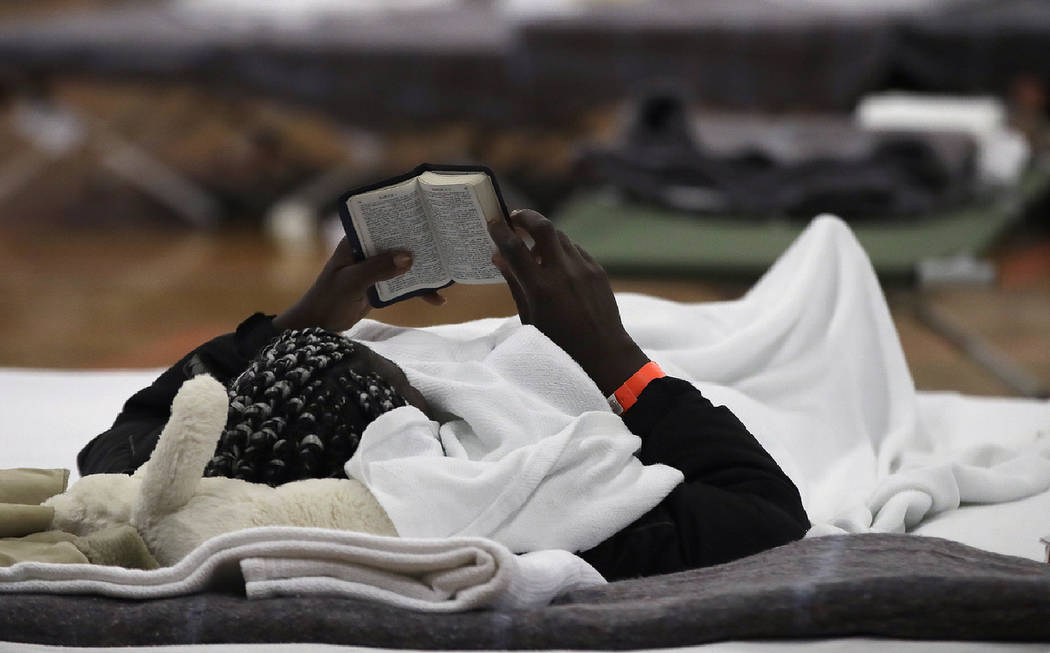 A migrant woman reads a Bible as she rests inside the Portland Exposition Building in Portland, ...