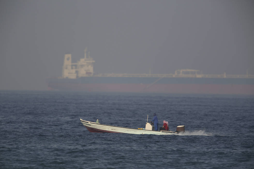 A fishing boat speeds past an oil tanker in the distance in Fujairah, United Arab Emirates, Sat ...