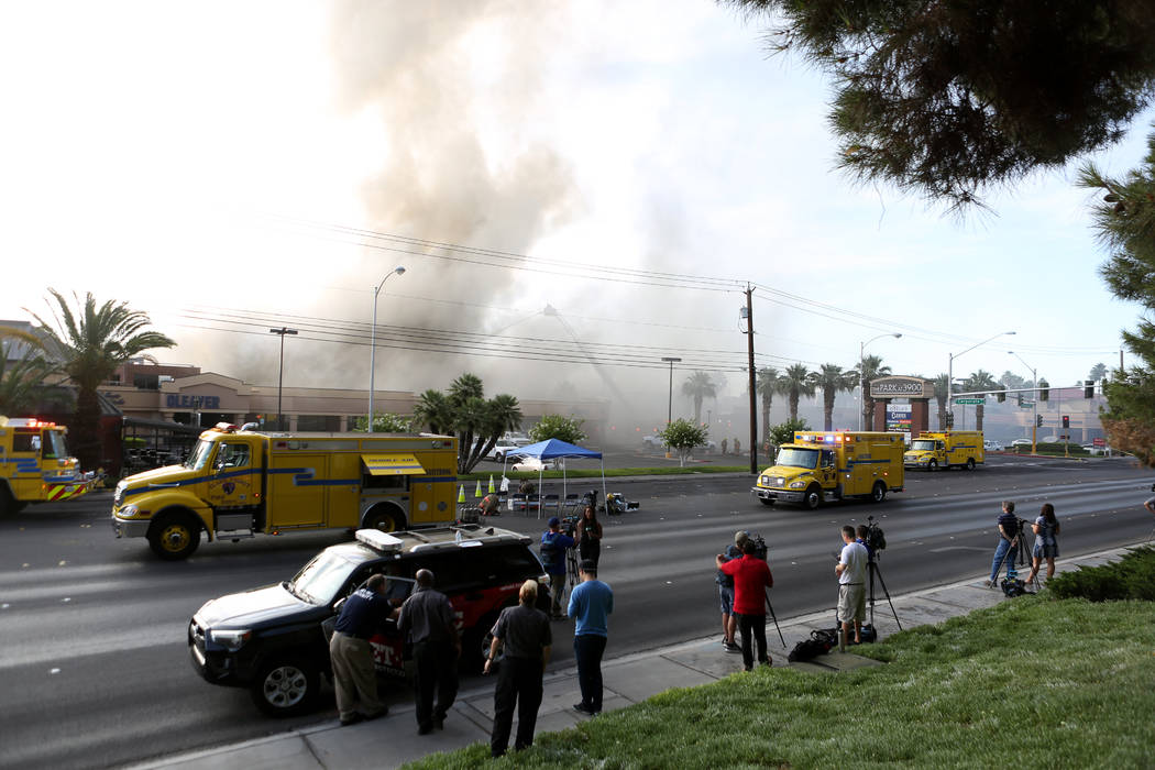 News media gather across the street from a business complex fire near Paradise Road and East Tw ...