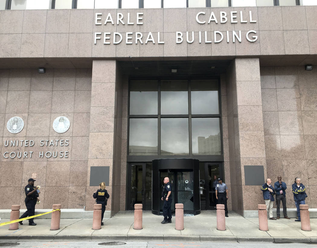 Law enforcement officers secure the scene after a man fired shots outside the Earle Cabell Fede ...