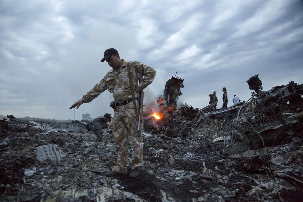 FILE - In this July 17, 2014 file photo, people walk amongst the debris at the crash site of a ...