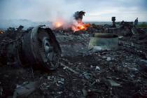 In a Thursday, July 17, 2014, file photo, a man walks amongst the debris at the crash site of a ...