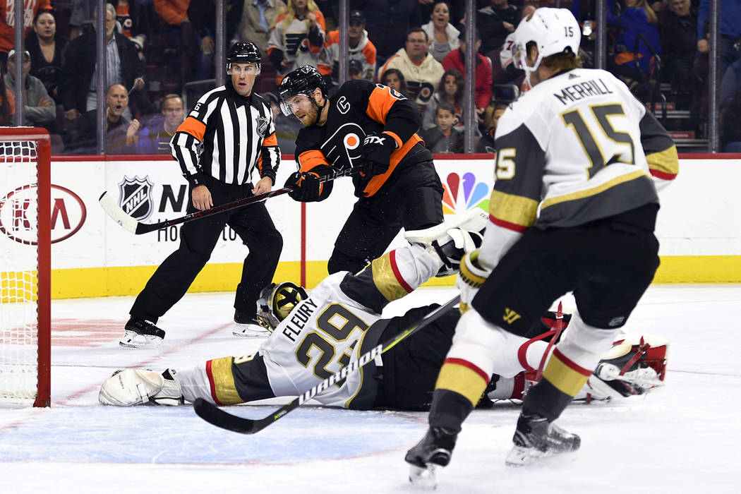 Philadelphia Flyers' Claude Giroux, center, watches the puck as Vegas Golden Knights' goaltende ...