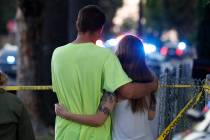 A man and woman watch as law enforcement officers surround a home where a gunman has taken refu ...