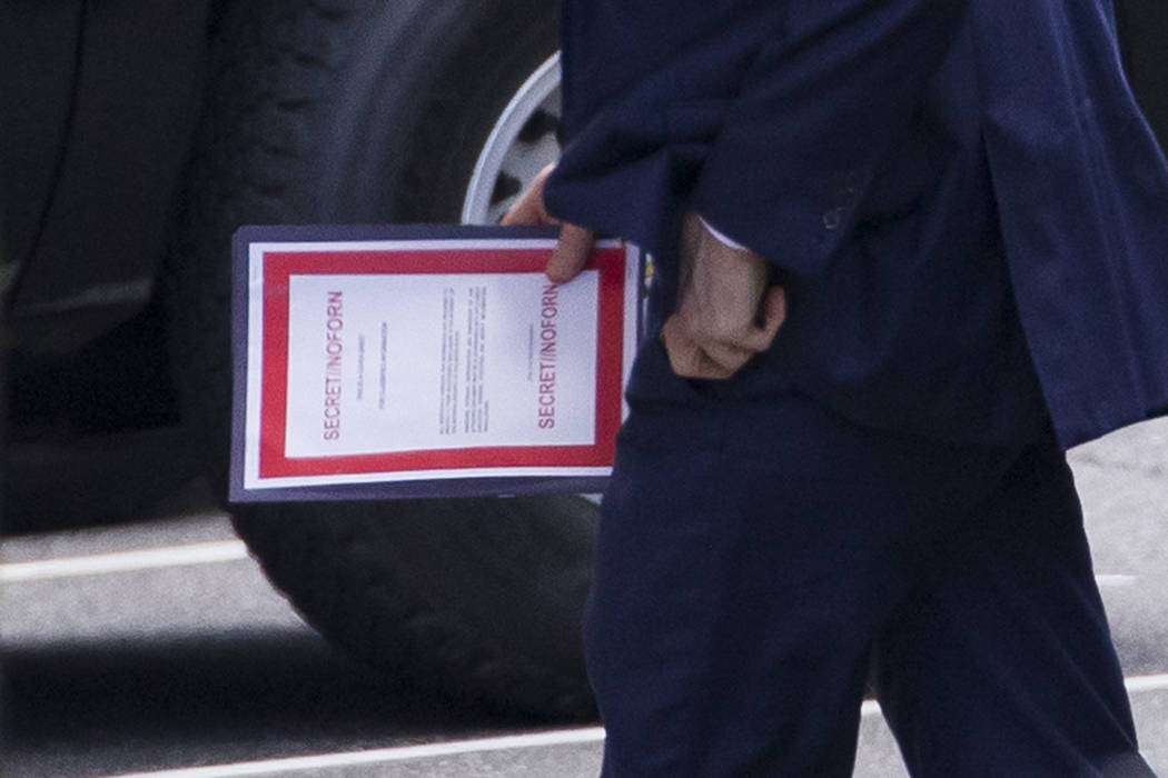 Outgoing acting Defense Secretary Patrick Shanahan carries a document labeled secret as he arri ...