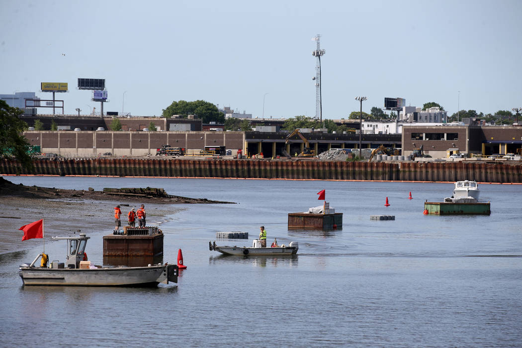 Workers prepare fireworks on barges on the Mystic River at Encore Boston Harbor in Everett, Mas ...