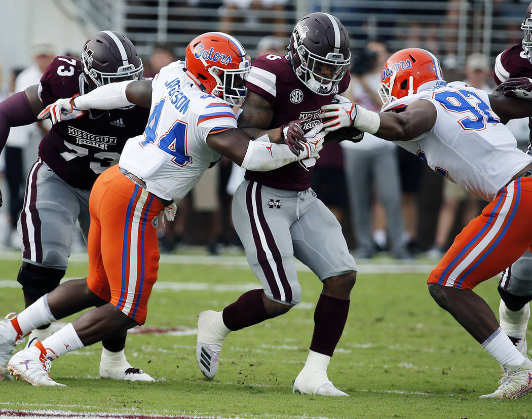 Mississippi State running back Kylin Hill (8) fights his way past Florida linebacker Rayshad Ja ...