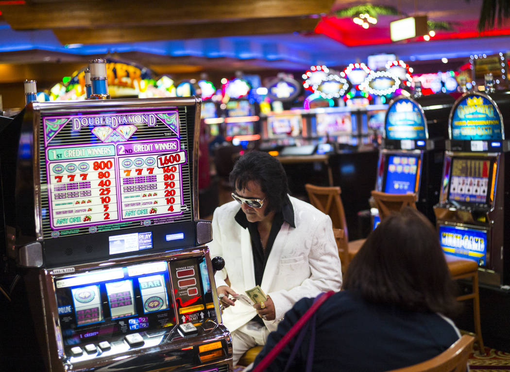 Elvis tribute artist Bobby Presley, of Modesto, Calif., sits by slot machines ahead of the '60s ...