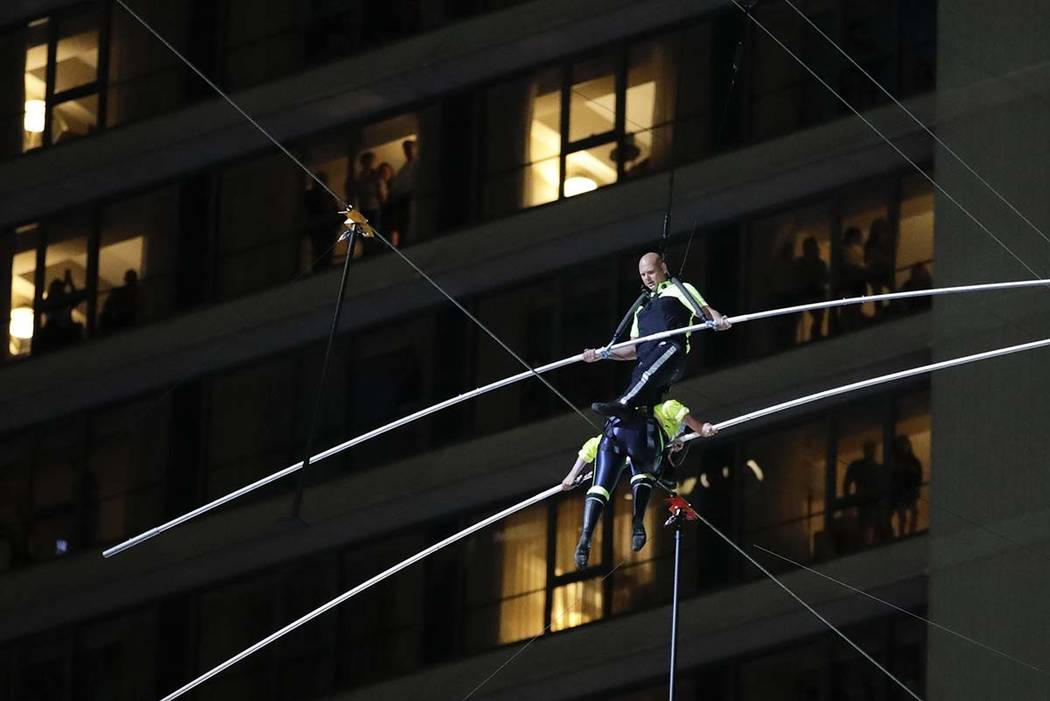 Aerialists Nik Wallenda, top, steps over his sister Lijana as they walk on a high wire above Ti ...