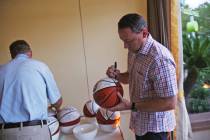 Jack Murphy, coach for Northern Arizona University, signs a basketball at the Coach vs. Cancer ...