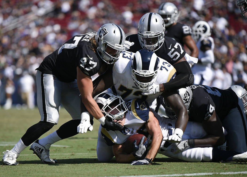 Los Angeles Rams running back Nick Holley runs the ball defended by Oakland Raiders linebacker ...