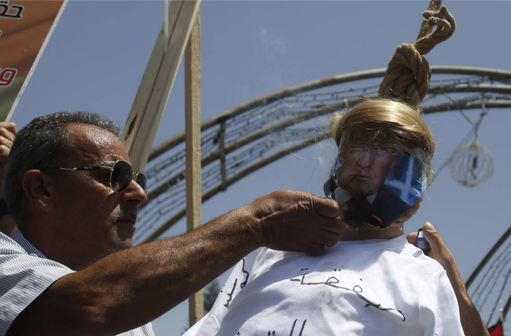 A Palestinian burns an effigy of the US President Donald Trump aduring a protest against the Am ...