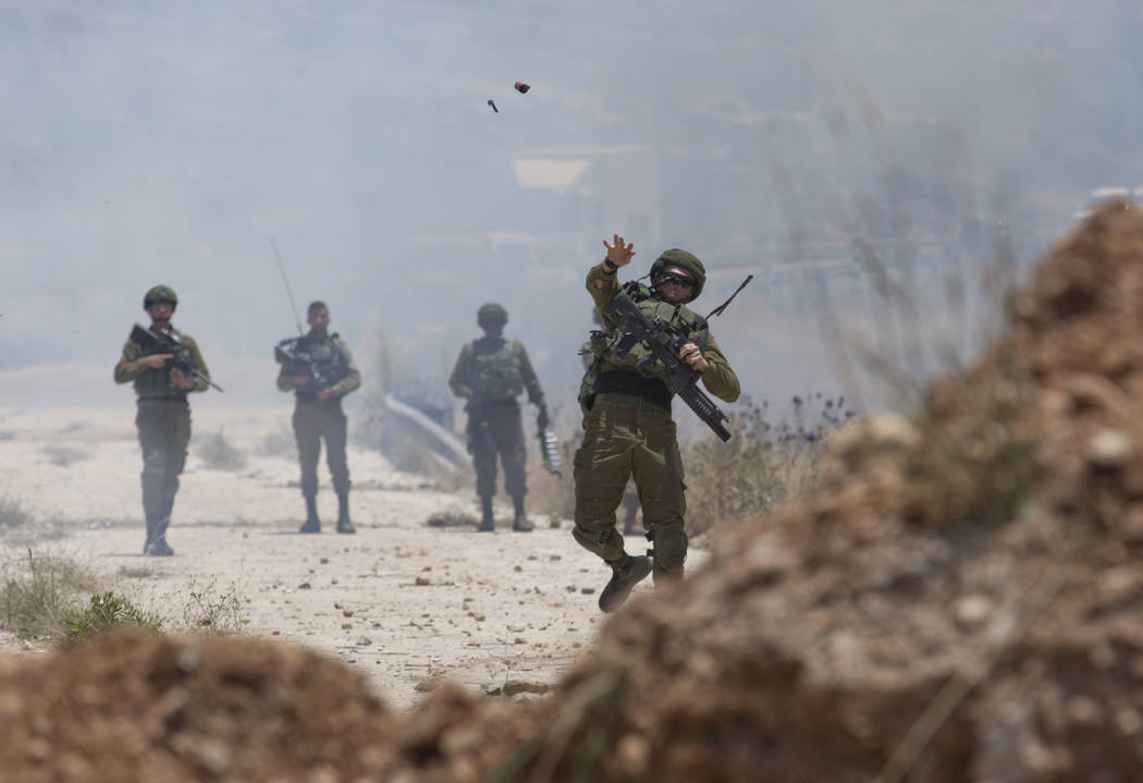 Israeli border police use teargas to disperse Palestinian protesters during a rally against the ...