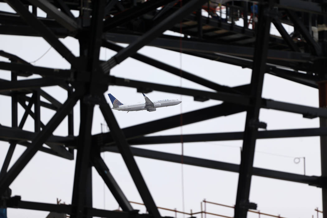A plane takes flight on the background of the Raiders stadium construction site in Las Vegas, T ...