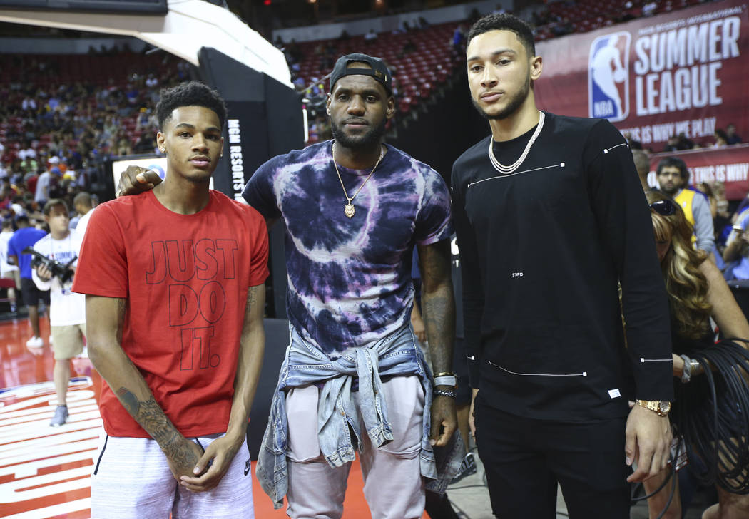 LeBron James, center, poses with Dejounte Murray, left, and Ben Simmons at halftime as the Los ...