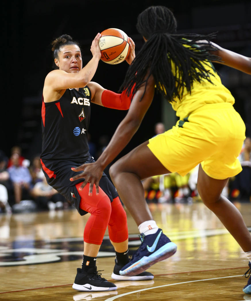 Las Vegas Aces guard Kayla McBride, left, looks to move the ball around Seattle Storm forward C ...