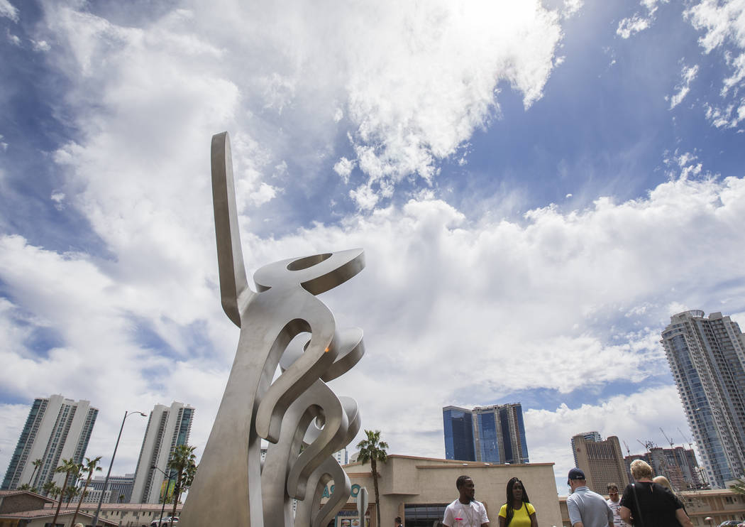 People walk by a new statue called "LOOK!" outside The Strat on Friday, April 19, 201 ...