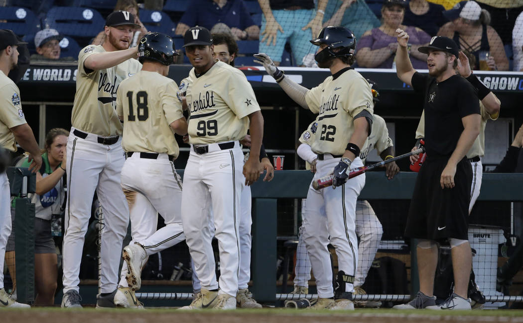 Vanderbilt's Pat DeMarco (18) is congratulated by teammates after scoring a run against Michiga ...