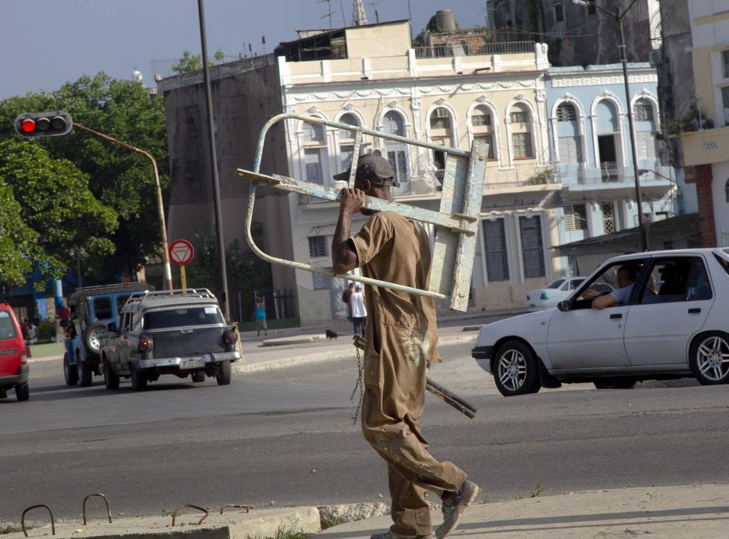 A worker carries scaffolding as he walks to a job in Havana, Cuba, Thursday, June 27, 2019. Cub ...
