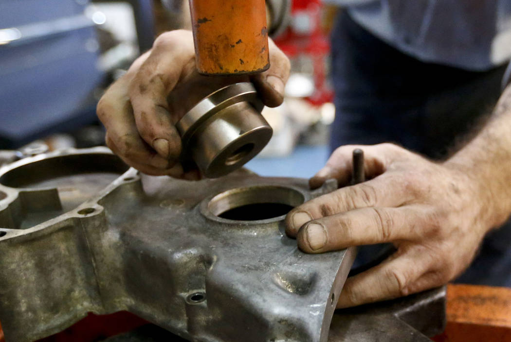 Automotive technician Paul Wegweiser uses a press to replace an engine seal at a repair shop in ...