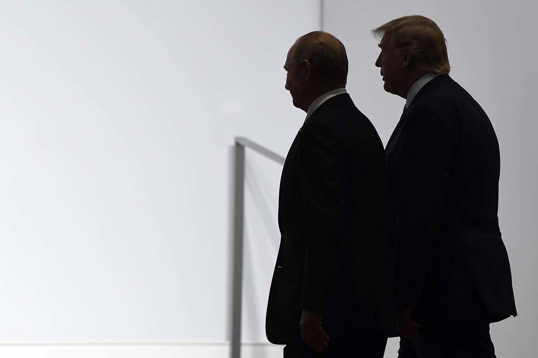 President Donald Trump and Russian President Vladimir Putin walk to participate in a group phot ...