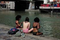 Girls wearing swimsuits sit along the Canal de l'Ourcq in Paris, Friday, June 28, 2019. Schools ...
