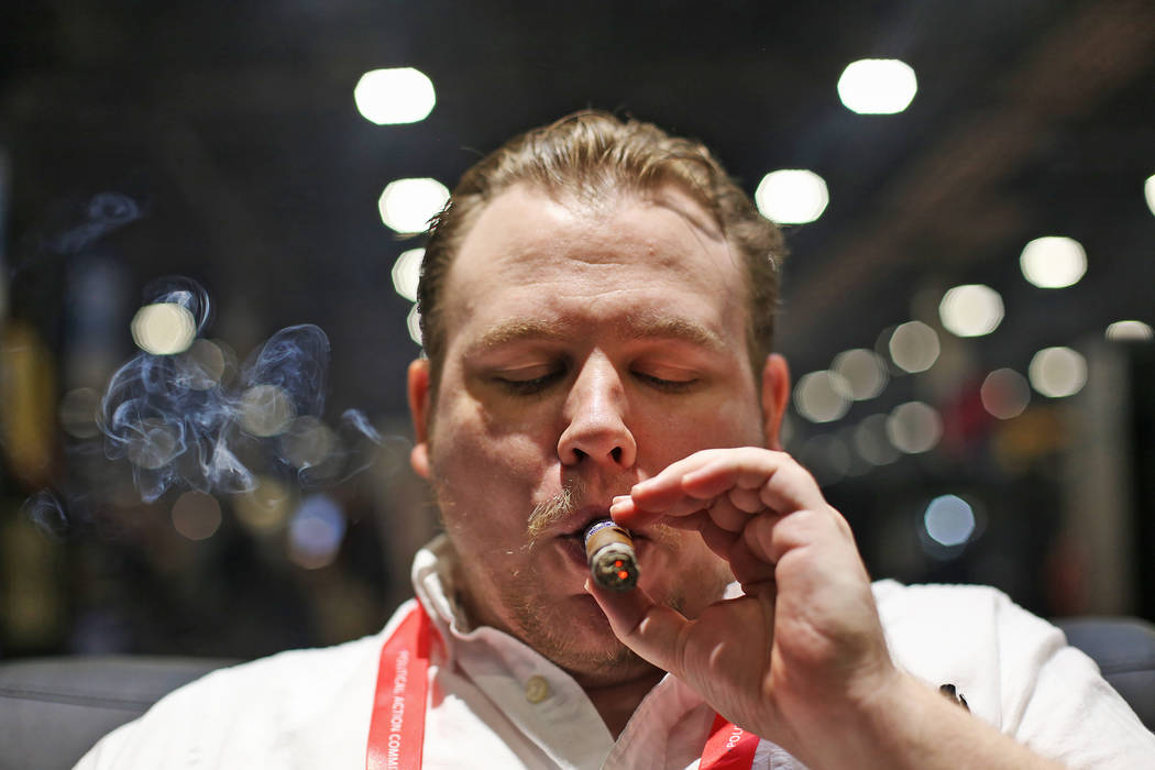 Ethan Bradon smokes a cigar at the Serino Cigar Company booth at the International Premium Ciga ...