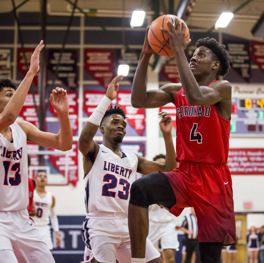 Coronado’s Tahj Comeaux (4) goes up for a shot while Liberty’s Davion Ware (23) ...