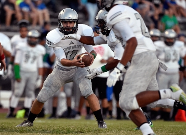 Green Valley quarterback A.J. Amelburu hands the ball off to his running back during a high ...