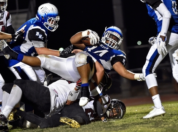 Basic&lsquo;s Sean White (34) rolls over Desert Oasis defenders as he makes forward progress ...