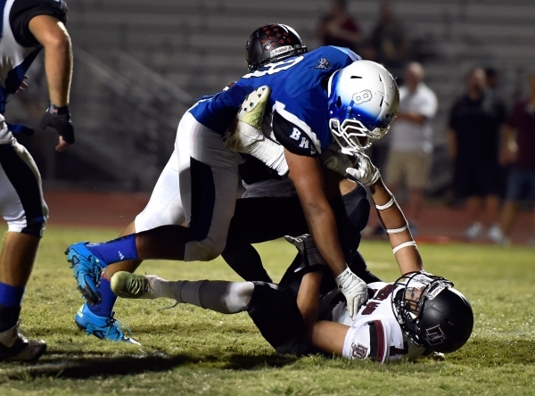 Basic&lsquo;s John Funaki (8) runs over Desert Oasis Branden Peterson as he rushes for touch ...