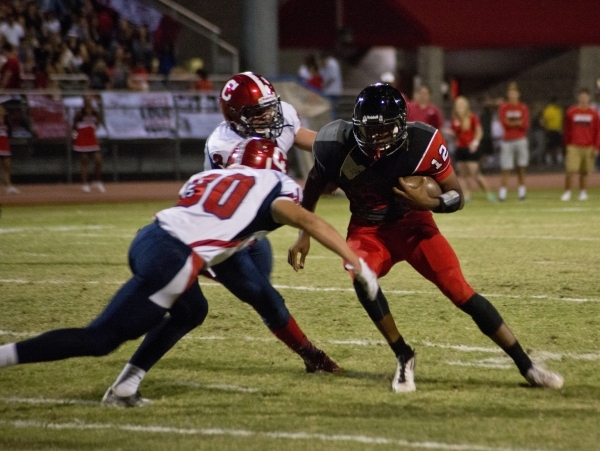 Las Vegas High School quarterback Zach Matlock (12) attempts to break tackles from Corey Leu ...