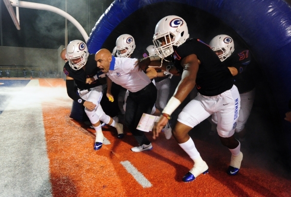 Bishop Gorman head coach Kenny Sanchez leads his team onto the field before the start of the ...